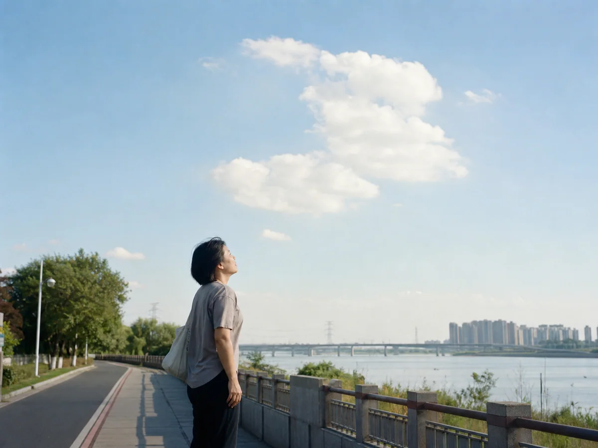 晴朗河堤上散步的人停下望云并拿起手机